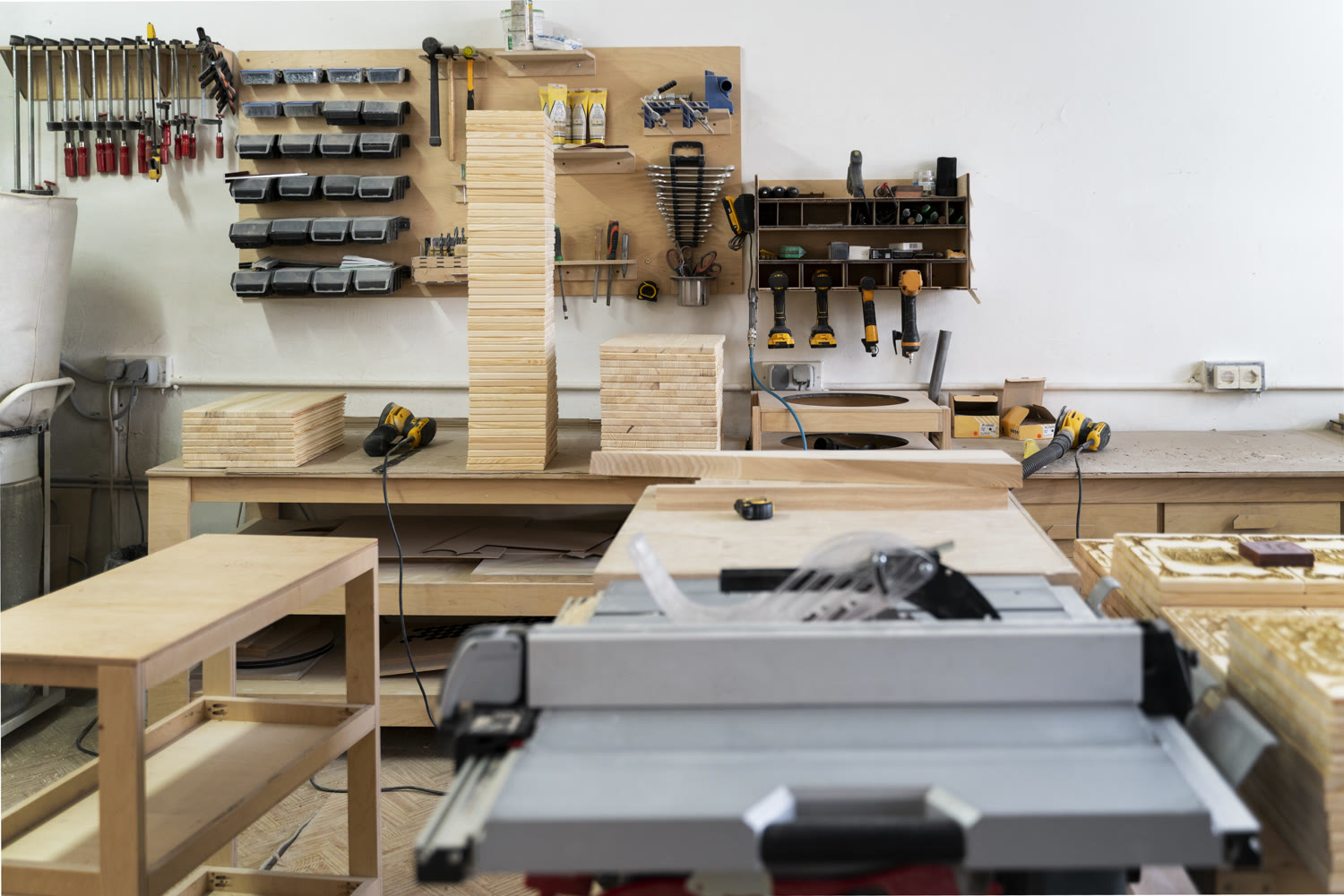 Mesa de trabajo del taller TRAMA con planos, herramientas y la marca grabada en madera